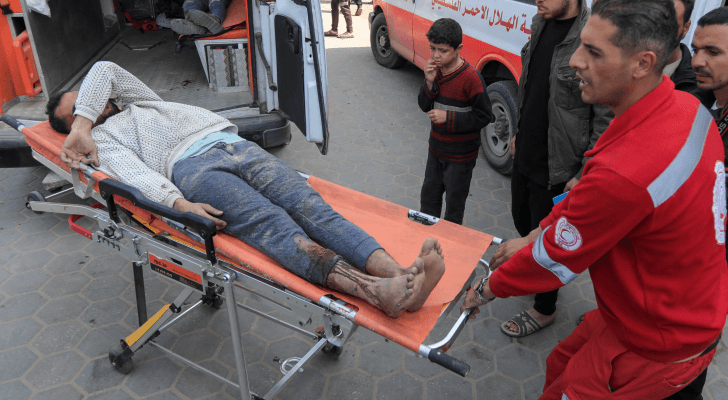 مسعف يحمل ينقل أحد الأشخاص الجرحى بعدوان الاحتلال على غزة