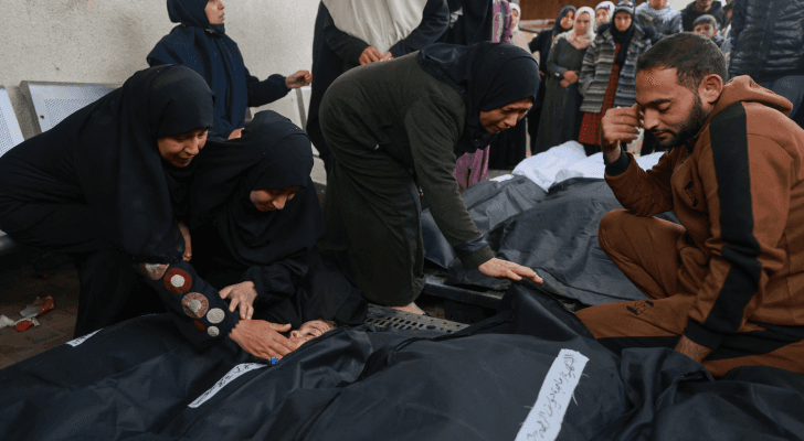 فلسطينيون بالقرب من شهداء جراء عدوان الاحتلال في مخيم رفح - AFP