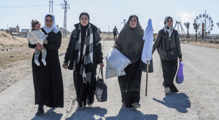 فلسطينيات نازحات يحملن أمتعتهن ورايات بيضاء أثناء سيرهن أمام قوات الاحتلال في خان يونس جنوبي قطاع غزة