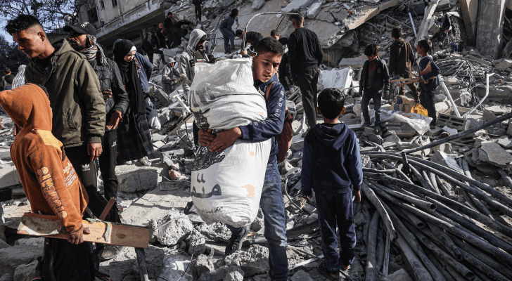 فلسطينيون يسيرون بين أنقاض مبنى سكني أصيب في غارة جوية للاحتلال في رفح جنوبي قطاع غزة