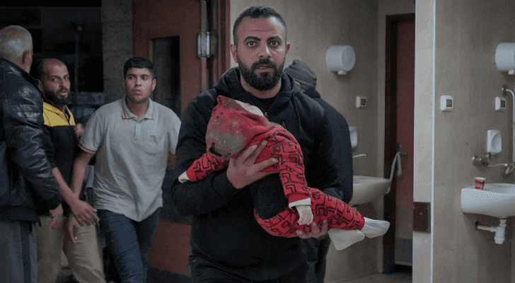فلسطيني يحمل صغيره الشهيد في غزة