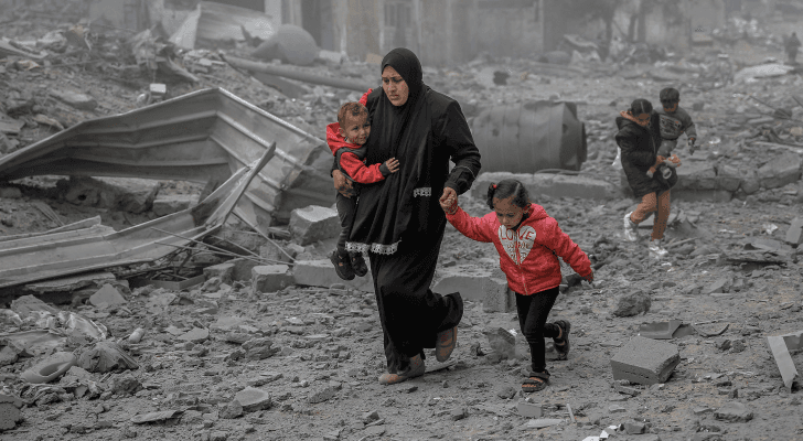 فلسطينية تحاول الوصول بأطفالها إلى مكان آمن في غزة