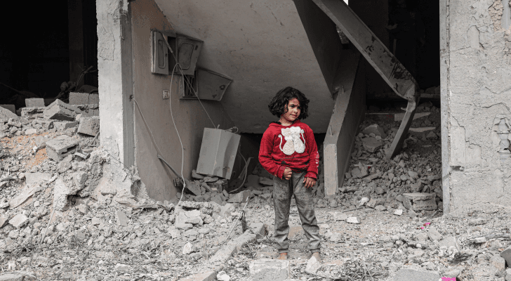 طفلة فلسطينية بالقرب من الأضرار التي لحقت بمبنى بعد قصف الاحتلال لرفح