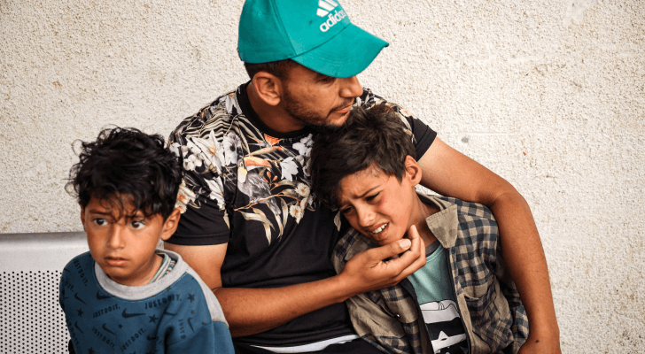 فلسطيني يحتضن أبناءه بعد استشهاد والدتهم في قطاع غزة