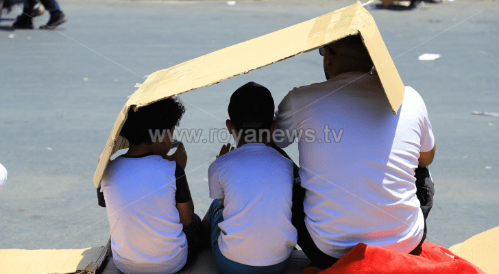 أب وأطفاله يستظلون بـ"قطعة كرتون" من أشعة الشمس في عمان