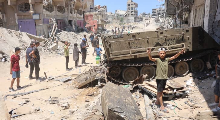 فتى فلسطيني يرفع علامة النصر بالقرب من دبابة للاحتلال الإسرائيلي