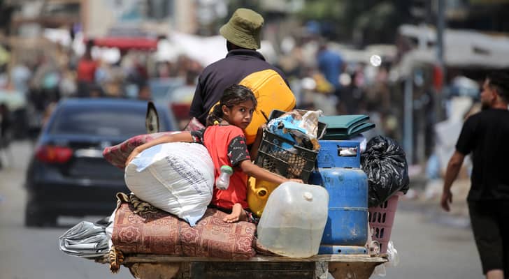 طفلm يجلس فوق عربة يجرها حمار بينما يفر الفلسطينيون بممتلكاتهم من دير البلح في وسط قطاع غزة