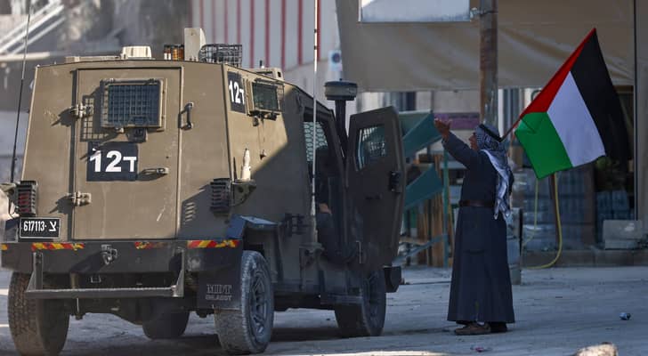 فلسطيني يرفع علم بلاده اأمام قوات الاحتلال