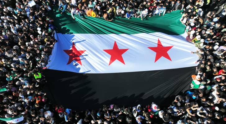 سوريون يرفعون علم الثورة السورية أثناء احتفالهم بسقوط نظام بشار الأسد