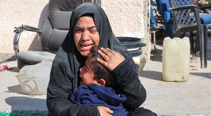 امرأة تبكي مع طفل بعد غارة للاحتلال على مدرسة المجيدة الوسيلة الحكومية التابعة للأونروا