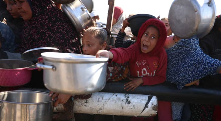 يقف فلسطينيون في انتظار حصة طعام في مركز توزيع جنوب خان يونس