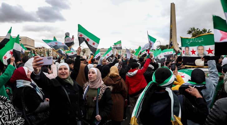 امرأة تلتقط صورة سيلفي بينما يلوح الناس بأعلام سورية من عصر الاستقلال خلال مظاهرة للاحتفال بسقوط الرئيس السوري بشار الأسد