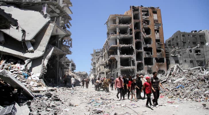 فلسطينيون يسيرون بين أنقاض المنازل في جباليا