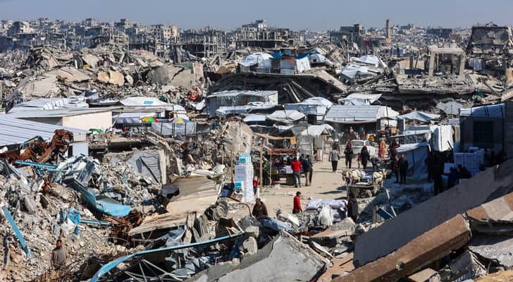 فلسطينيون بالقرب من أنقاض المباني المدمرة في جباليا شمال قطاع غزة