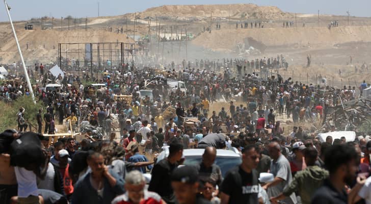 فلسطينيون نازحون يحملون مساعدات إغاثية أثناء عودتهم من مركز لتوزيع المساعدات في وسط قطاع غزة
