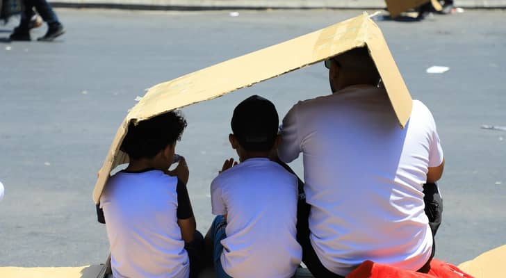 شخص وأطفاله يستظلون من أشعة الشمس في عمان