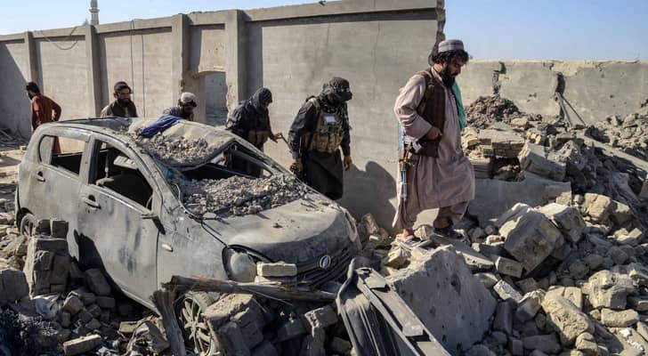 أفراد أمن من طالبان يسيرون أمام سيارة متضررة في منطقة سبين بولداك في ولاية قندهار
