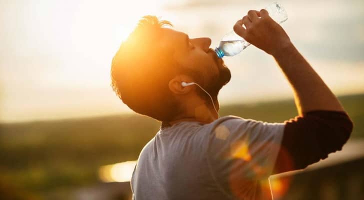 شاب يشرب مياه وسط حرارة الشمس